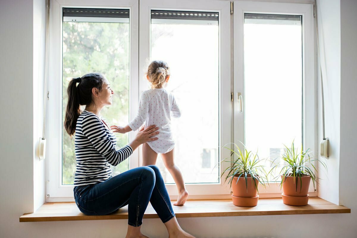 Mother with young child looking out window